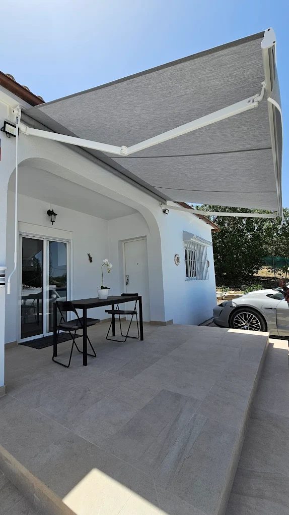 Toldo de cofre gris extendido sobre el porche de una vivienda