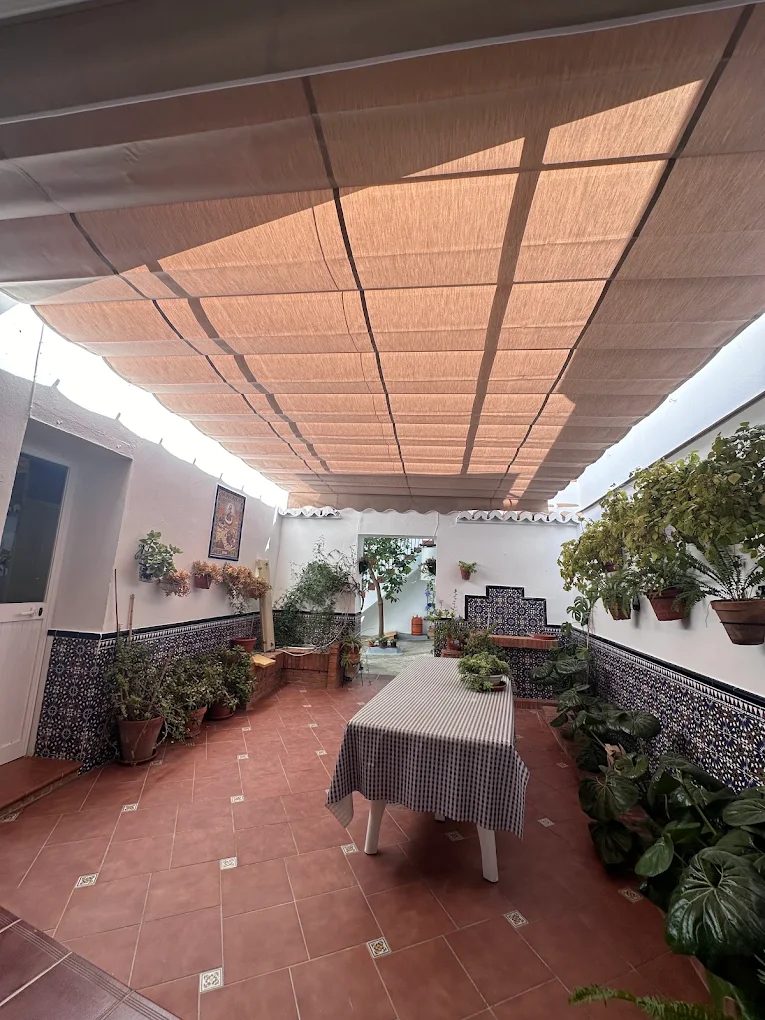 Toldo corredero de lona beige cubriendo un patio andaluz